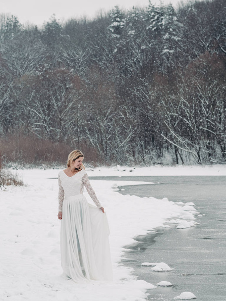 Braut stakst draußen vor der weißen Natur. Winterhochzeit.  - Foto, Bild