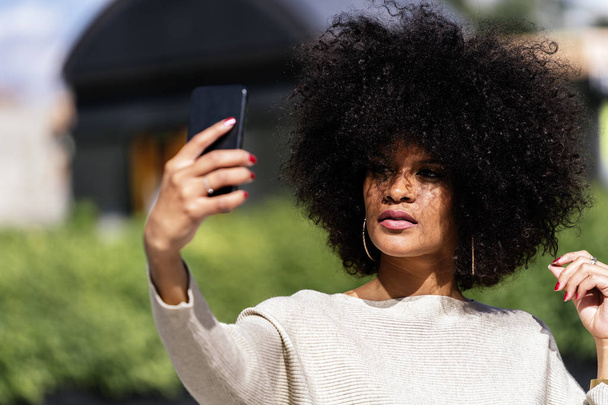 Portrait of attractive afro woman taking selfie portrait in the street - Foto, imagen