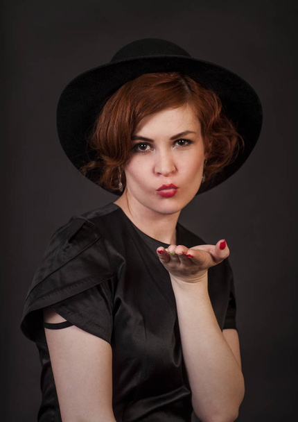 Emotional brunette posing in the Studio in a hat.Isolated image on dark background. - Valokuva, kuva