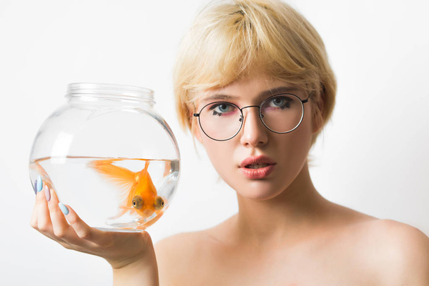 Portrait of a beautiful girl with a goldfish in an aquarium. - Valokuva, kuva