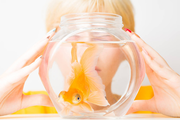 Portrait of a beautiful girl with a goldfish in an aquarium. - Φωτογραφία, εικόνα