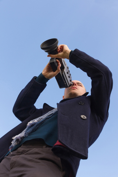 Jeune filmant avec une caméra de film super 8 mm vu d'en bas et fond de ciel
  - Photo, image