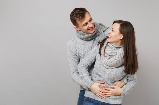 Young cute couple girl guy in gray sweaters, scarves together isolated on grey wall background, studio portrait. Healthy lifestyle, ill sick disease treatment, cold season concept. Mock up copy space - Photo, Image