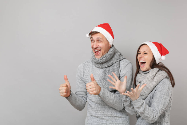Hauskaa pari tyttö kaveri punainen Santa Christmas hattu harmaa villapaidat huivit eristetty harmaa seinä tausta, studio muotokuva. Hyvää uutta vuotta 2019 juhla juhlakonsepti. Mallintaa kopiotilaa
 - Valokuva, kuva