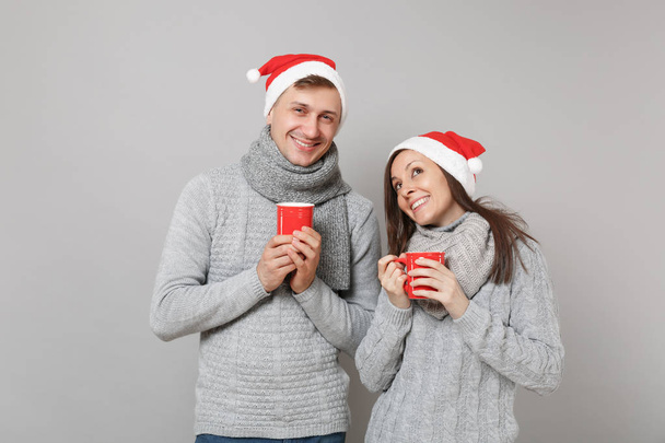 Kırmızı Santa Noel şapka gri kazak eşarp eğlenceli çift kız adam gri duvar arka planda, stüdyo portre izole çay bardak tutun. Mutlu yeni yıl 2019 tatil parti kavramı. Kopyalama alanı alay - Fotoğraf, Görsel