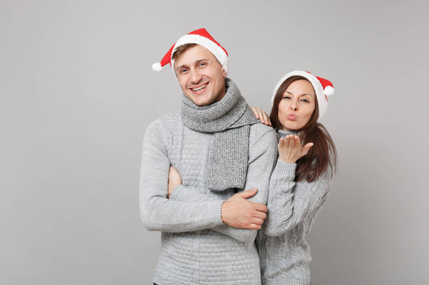 Joyeux couple amusant fille gars en rouge Santa Noël chapeau chandails gris écharpes isolées sur fond de mur gris, portrait studio. Bonne année 2019 fête fête concept de fête. Maquette espace de copie
 - Photo, image