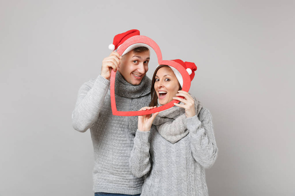 Veselé zábavy pár věrnost v červené vánoční Santa klobouk šedé svetry šály izolovaných na šedou stěnu pozadí, Studiový portrét. Šťastný nový rok 2019 oslavu dovolenou stranou koncept. Vysmívat se kopie prostor - Fotografie, Obrázek
