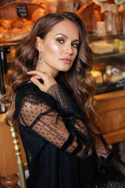 fashion interior photo of beautiful woman with dark hair in elegant dress posing in elegant bakery cafe - Fotografie, Obrázek