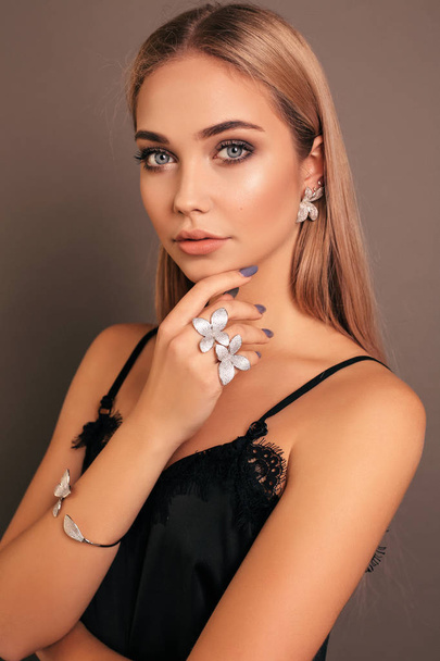 fashion photo of beautiful young girl with blond hair in elegant black dress with jewelry posing in studio - Fotoğraf, Görsel