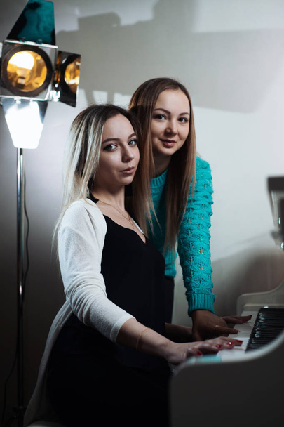 Two young beautiful girls playing the piano. Girls learn to play a musical instrument. - Foto, afbeelding