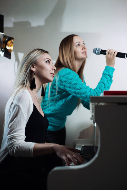 Beautiful young girl playing the piano and her friend sings into the microphone - Φωτογραφία, εικόνα