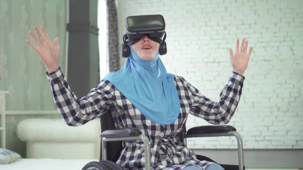 woman in hijab, wheelchair, uses VR glasses, 3D technology - Video, Çekim