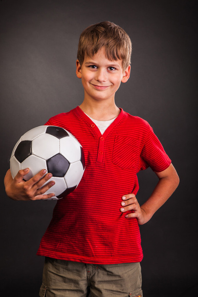 Cute boy is holding a football ball. Soccer ball - Фото, изображение