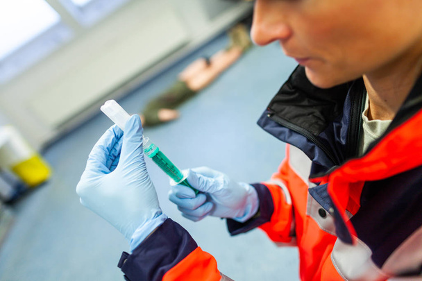 German paramedic picks up a syringe for a patient - Фото, изображение