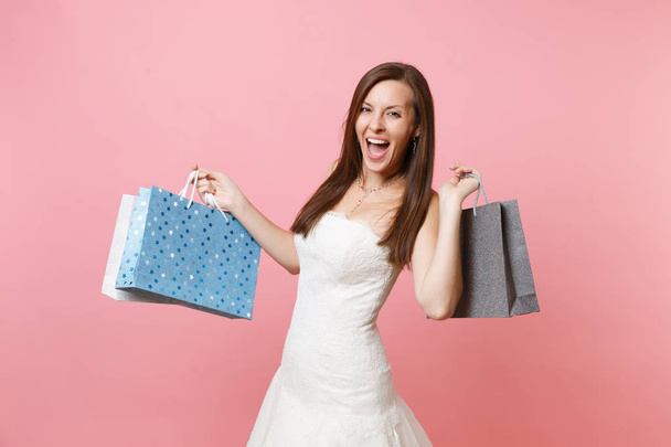 Portret podekscytowany radosny Panna młoda kobieta w sukni ślubnej koronki gospodarstwa wielo kolorowe opakowania torby z zakupami, po zakupy na białym tle na różowym tle. Organizacja ślubu koncepcji. Miejsce - Zdjęcie, obraz