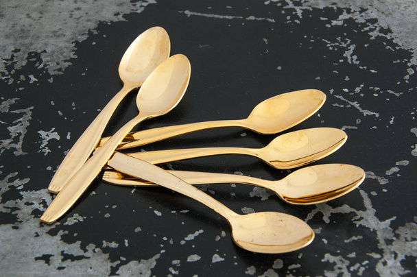 Vintage golden tea spoons on black background. Copy space for text. - Photo, image