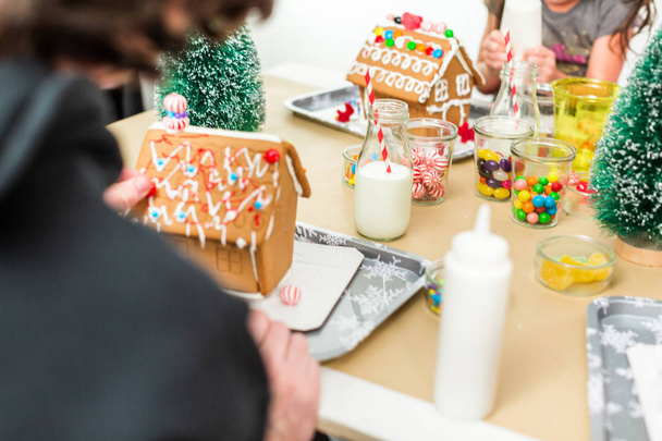 Kids decorating small gingerbread houses at the Christmas craft party. - Photo, Image