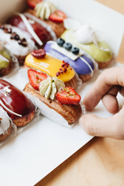 male hand taking delicious sweets with glaze, colorful dessert  - Photo, Image
