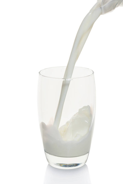 Milk is poured into a glass on white background - Zdjęcie, obraz