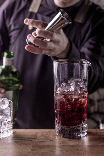 camarero con cóctel en vaso agitado preparando cóctel en el bar. bebidas alcohólicas, personas y concepto de lujo
 - Foto, Imagen