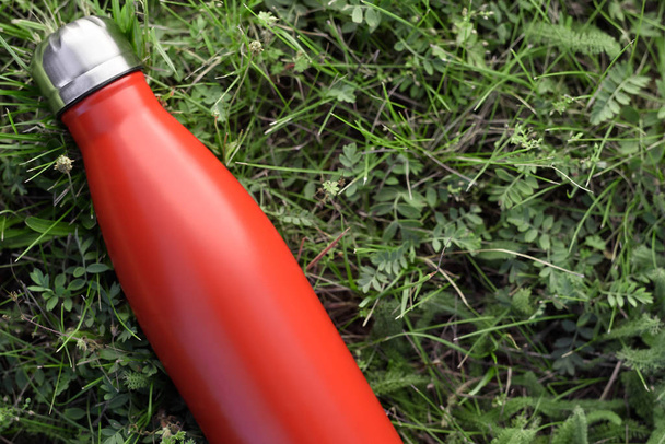 Stainless bottle thermos, red color. On the green grass background - Photo, Image