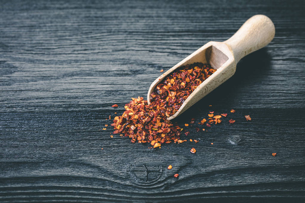 dry hot pepper in a scoop on black wooden background - Foto, Imagem