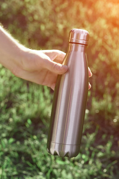 Stainless thermos bottle for liquid, in human hand - Photo, Image