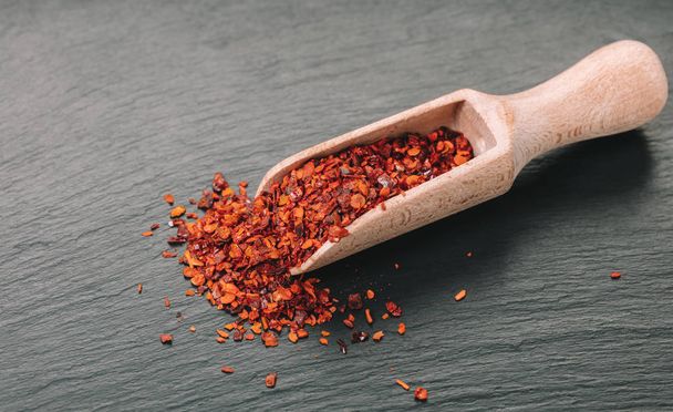 dry hot pepper in a scoop on black background - Foto, imagen