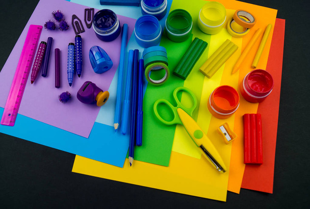 School accessories are laid out in the form of a rainbow. Black background.Happy back to school student. Art and crafts for kids. Child learning rainbow colors, alphabet letters and numbers. - Photo, image