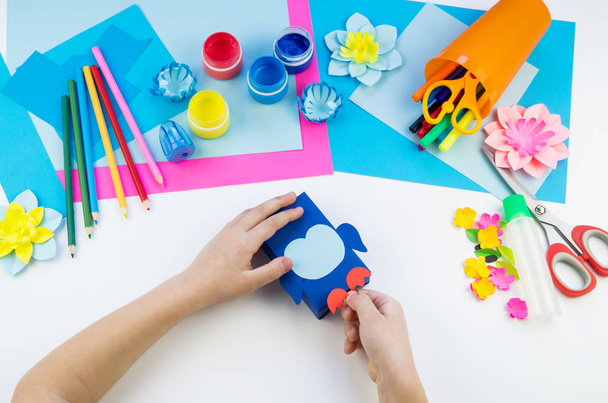Child hands making a penguin out of paper. Application of children's creativity. Kindergarten and craft school. White background and materials for crafts. - Φωτογραφία, εικόνα