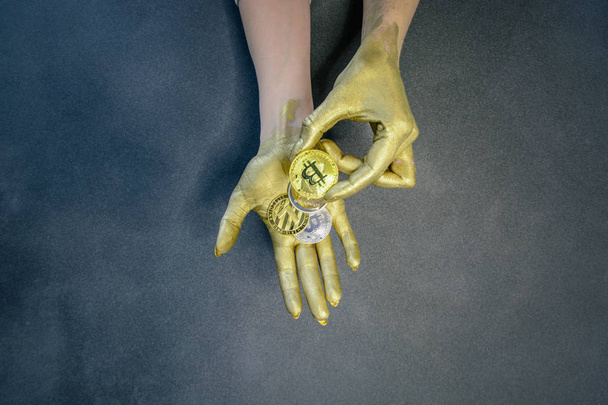 bitcoin, litecoin and ethereum lie in woman palms painted with golden paint - Photo, image
