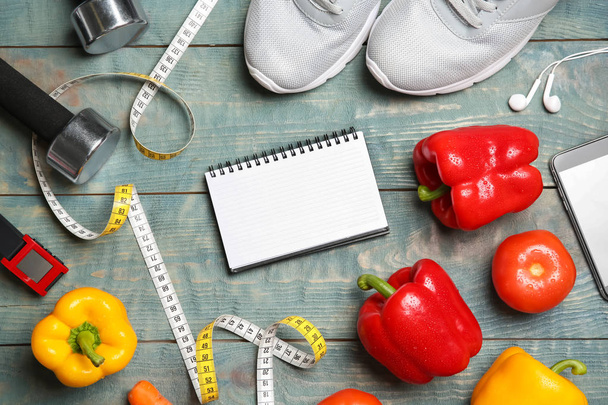 flache Liegekomposition mit Sportartikeln, gesunder Ernährung, Notizbuch und Platz für Text auf Holzgrund. Gewichtsverlust-Konzept - Foto, Bild