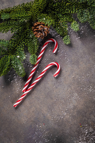 Christmas background, pine cones, red striped canes on background with Fir branches. Xmas and Happy New Year composition. Flat lay, top view. - Fotó, kép