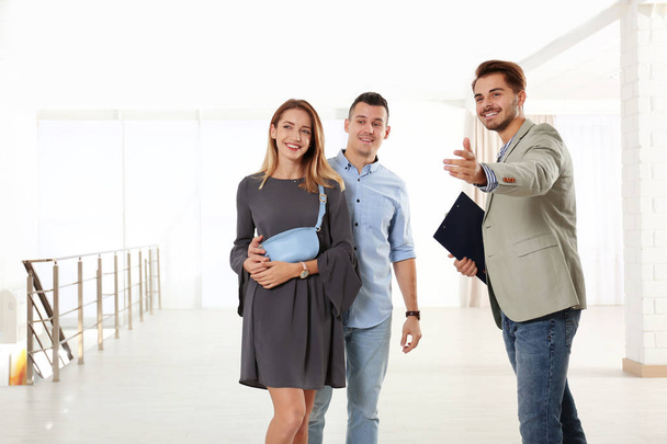 Real estate agent showing new apartment to young couple - Foto, afbeelding