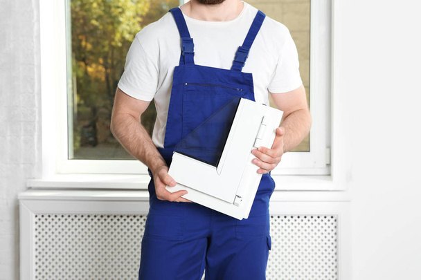 Installation worker with sample of modern window profile indoors - Photo, image