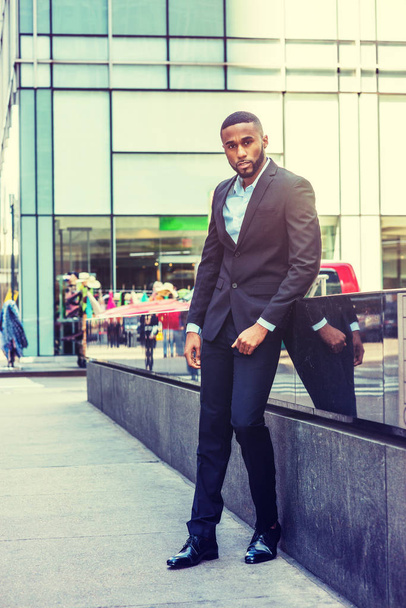 Portrait of Young African American Businessman. Young black Man with beard travel in New York, wearing black jacket, pants, leather shoe, standing on street in Middletown of Manhattan, looking forward - Fotó, kép