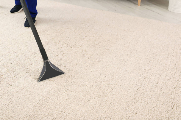 Man removing dirt from carpet with vacuum cleaner indoors, closeup. Space for text - Foto, afbeelding