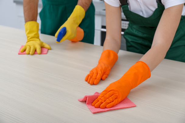 Team of janitors cleaning table in kitchen, closeup - Foto, Imagen
