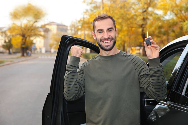 Young man holding car key near auto. Driving license test - Φωτογραφία, εικόνα