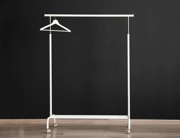 Wardrobe rack with hanger near dark wall - Foto, imagen