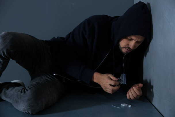 Young addicted man with drugs lying on floor - Фото, зображення