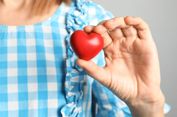 Mujer sosteniendo corazón decorativo rojo, vista de cerca
 - Foto, Imagen