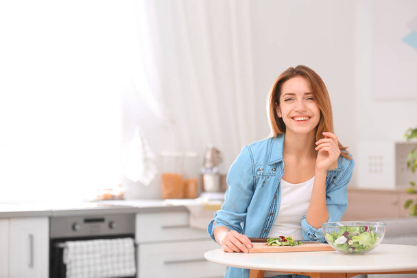Happy young woman preparing salad in kitchen, space for text. Healthy diet - Foto, Imagem