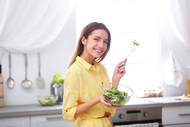 Happy young woman eating salad in kitchen. Healthy diet - Foto, Imagem
