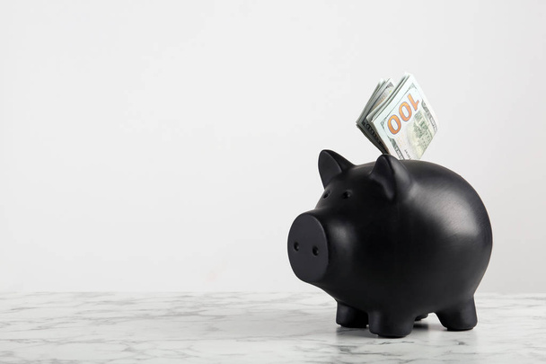 Piggy bank with dollar banknotes on table against white background. Space for text - Foto, afbeelding