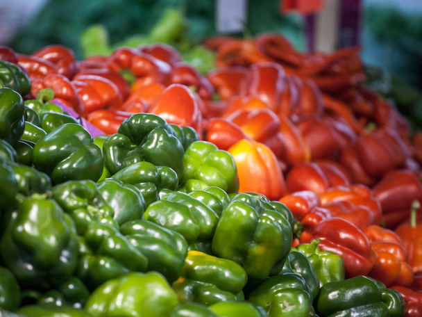 Red and green bell peppers for sale on a market of Canada. Peppers are a vegetal typical from the autumn - 写真・画像