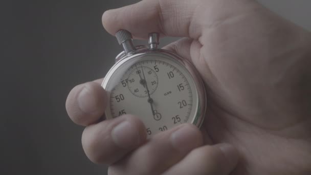 Close-up van één persoon een stopwatch op grijze achtergrond opstarten. 4k, 10 Bit, 4:2:2. - Video