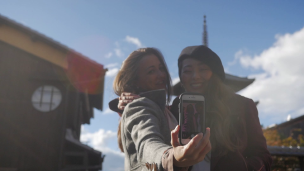 Kauniita kansainvälisiä turisteja ottaa selfie kanssa temppeli Kiotossa, sunflair, HD, hidastettuna
. - Materiaali, video