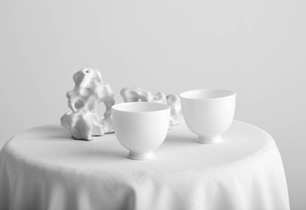 Witte tafel met witte thee bekers op witte muur achtergrond - Foto, afbeelding
