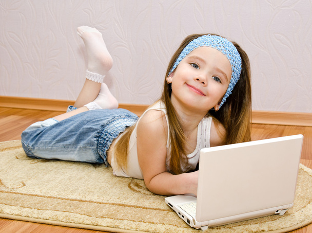 Mosolygós kislány a laptop otthon, az emeleten - Fotó, kép